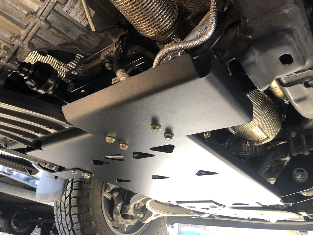 Skid plate fitted under a Ram 1500, seen from below at an angle with the front wheel beyond