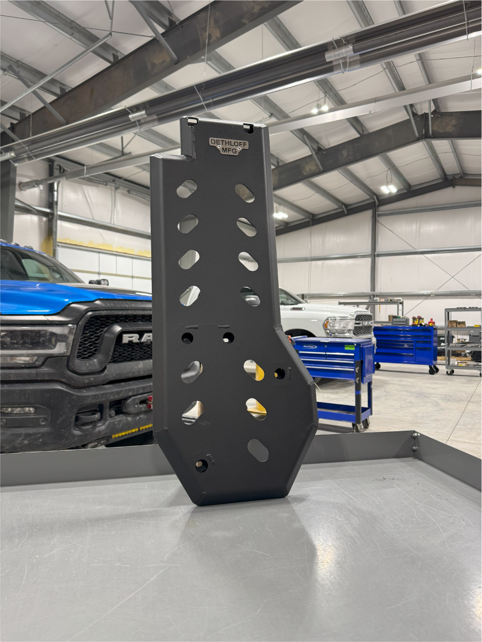 The guard standing on a bench in the shop, lightening holes across its face and trucks behind