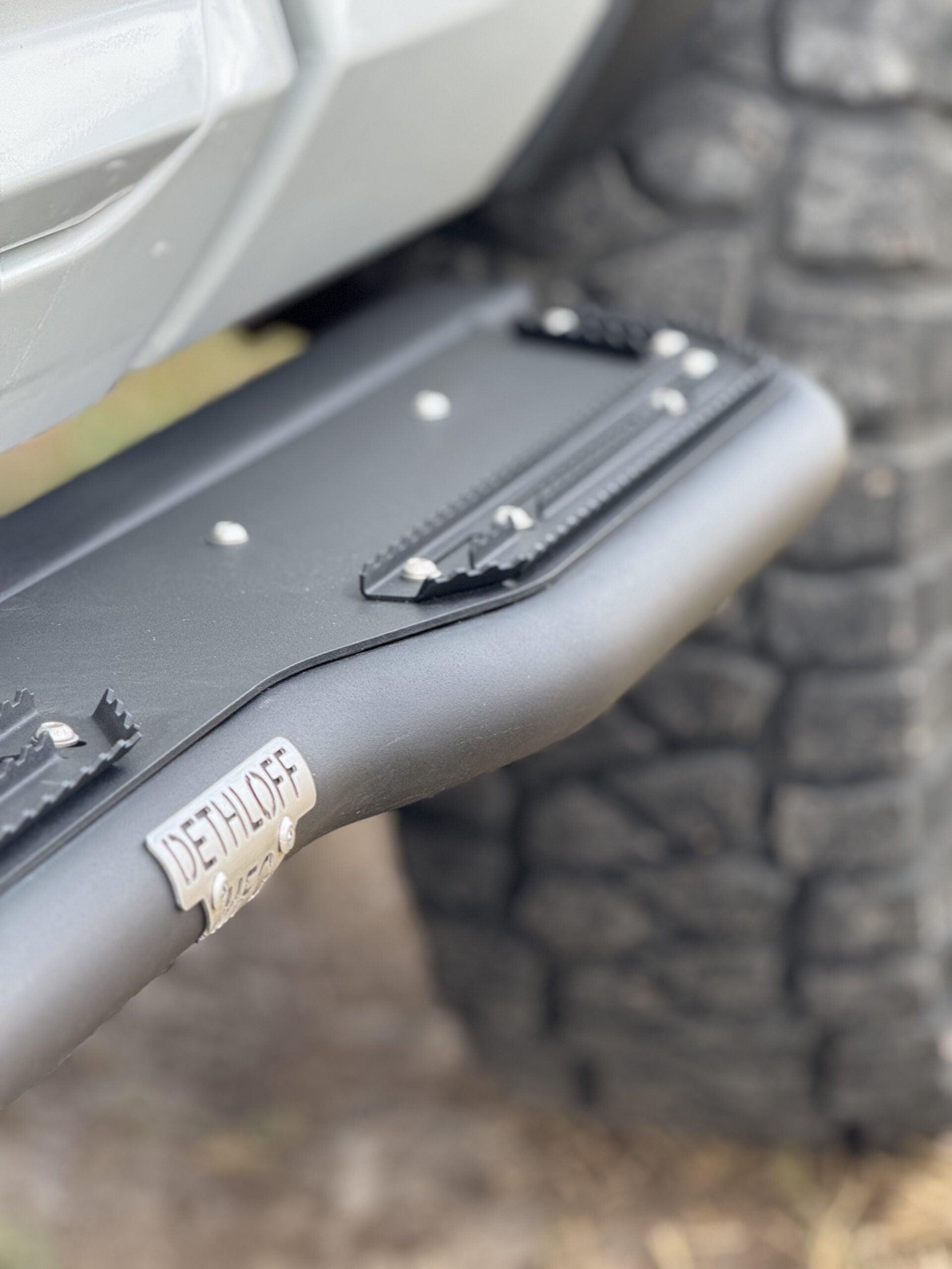 Close view of the slider's toothed grip strips and a DETHLOFF MFG badge on its face