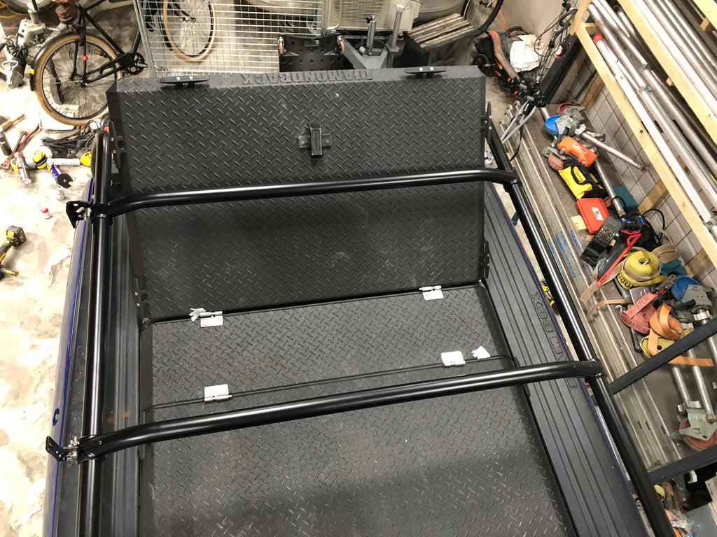 Looking down into the bed at the folded tonneau panels between the rack rails