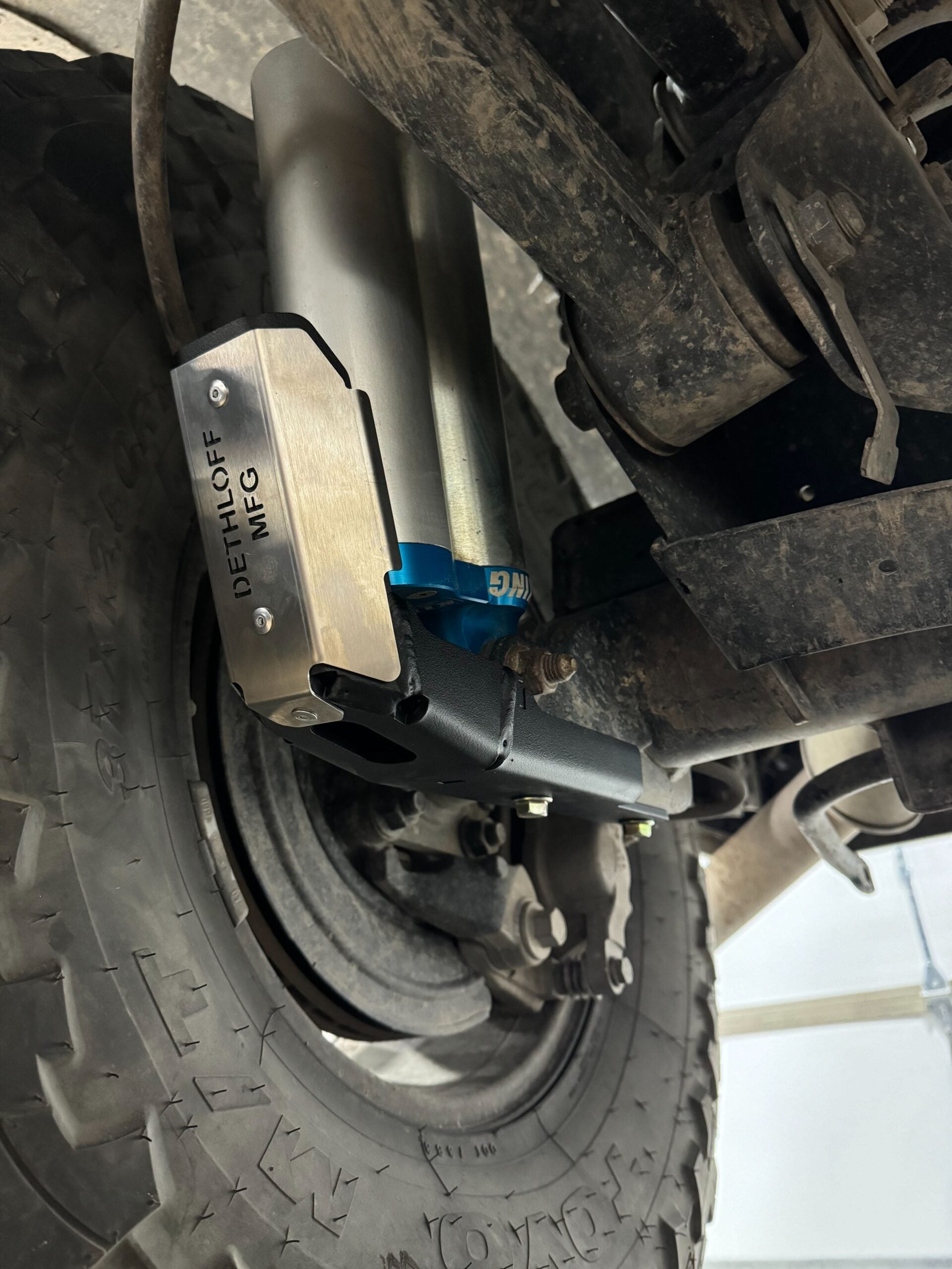 Shock guard clamped on the rear shock, its badge facing out and the tire below