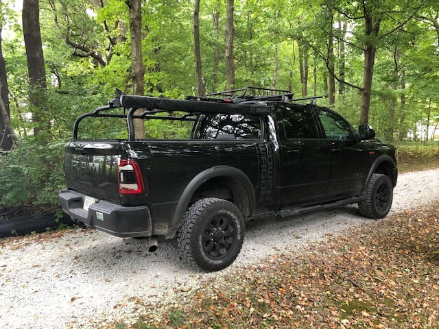 Rear quarter of the black Power Wagon on gravel, rack fully loaded