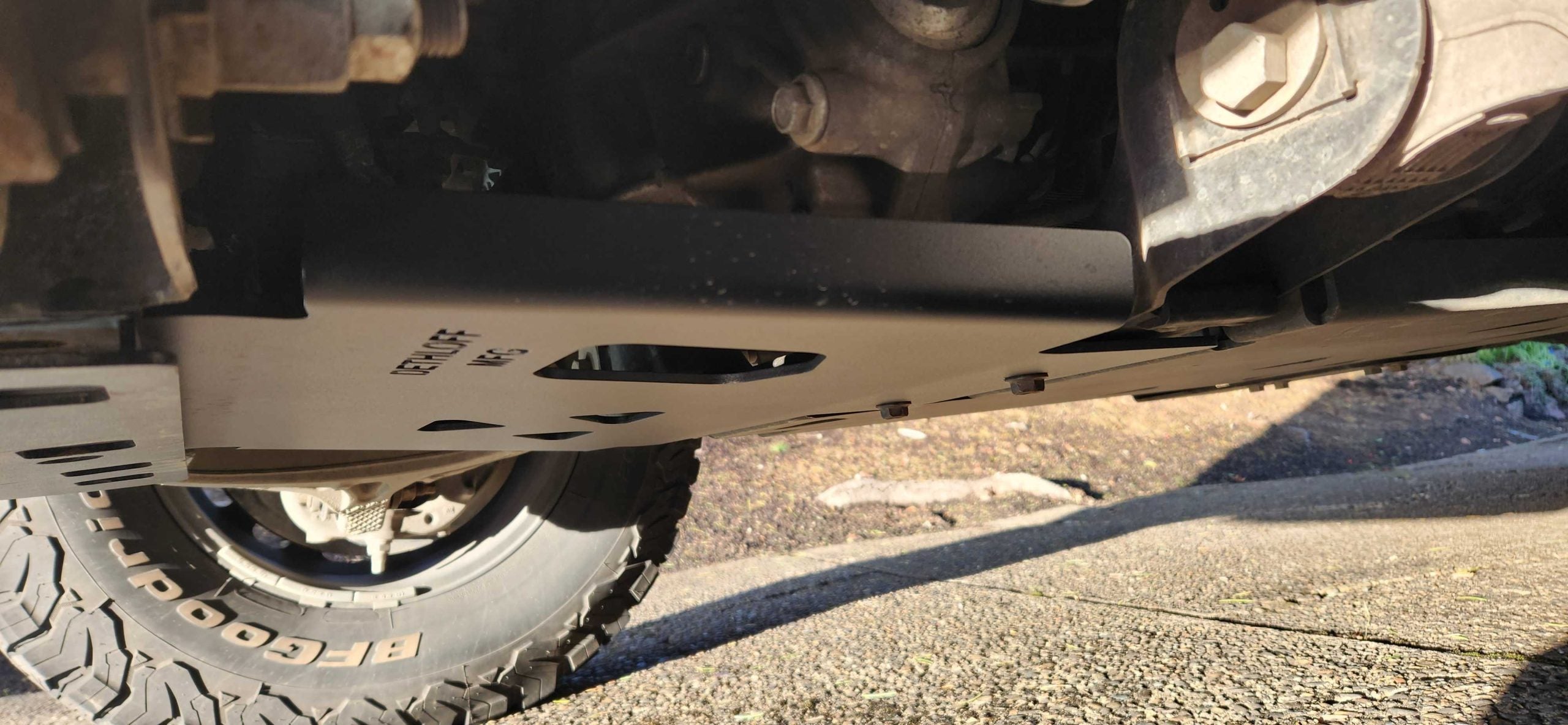 The plate fitted, seen past the front tire from outside the truck
