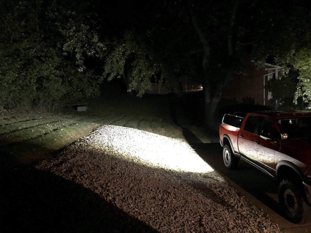 The truck at night on a gravel drive, its rack lights throwing a wide beam ahead