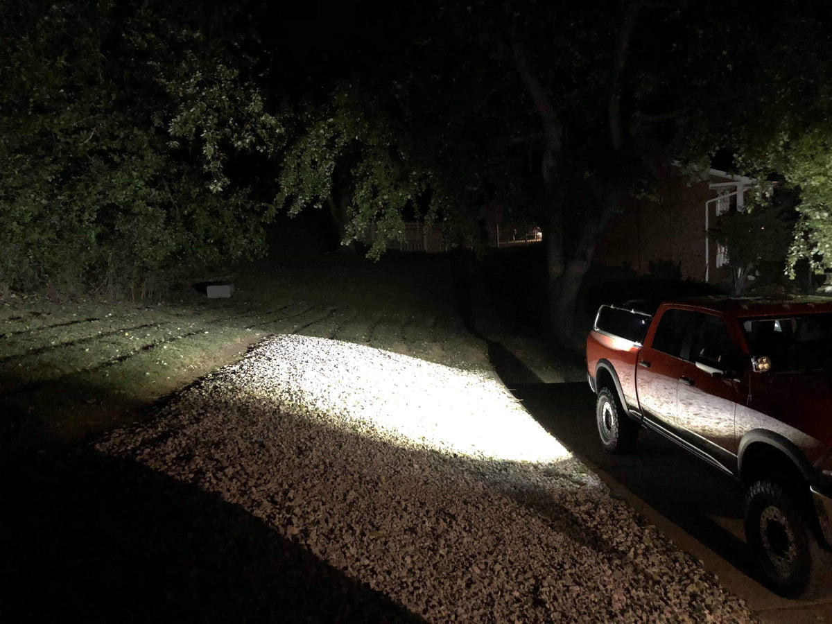 The truck at night on a gravel drive, its rack lights throwing a wide beam ahead
