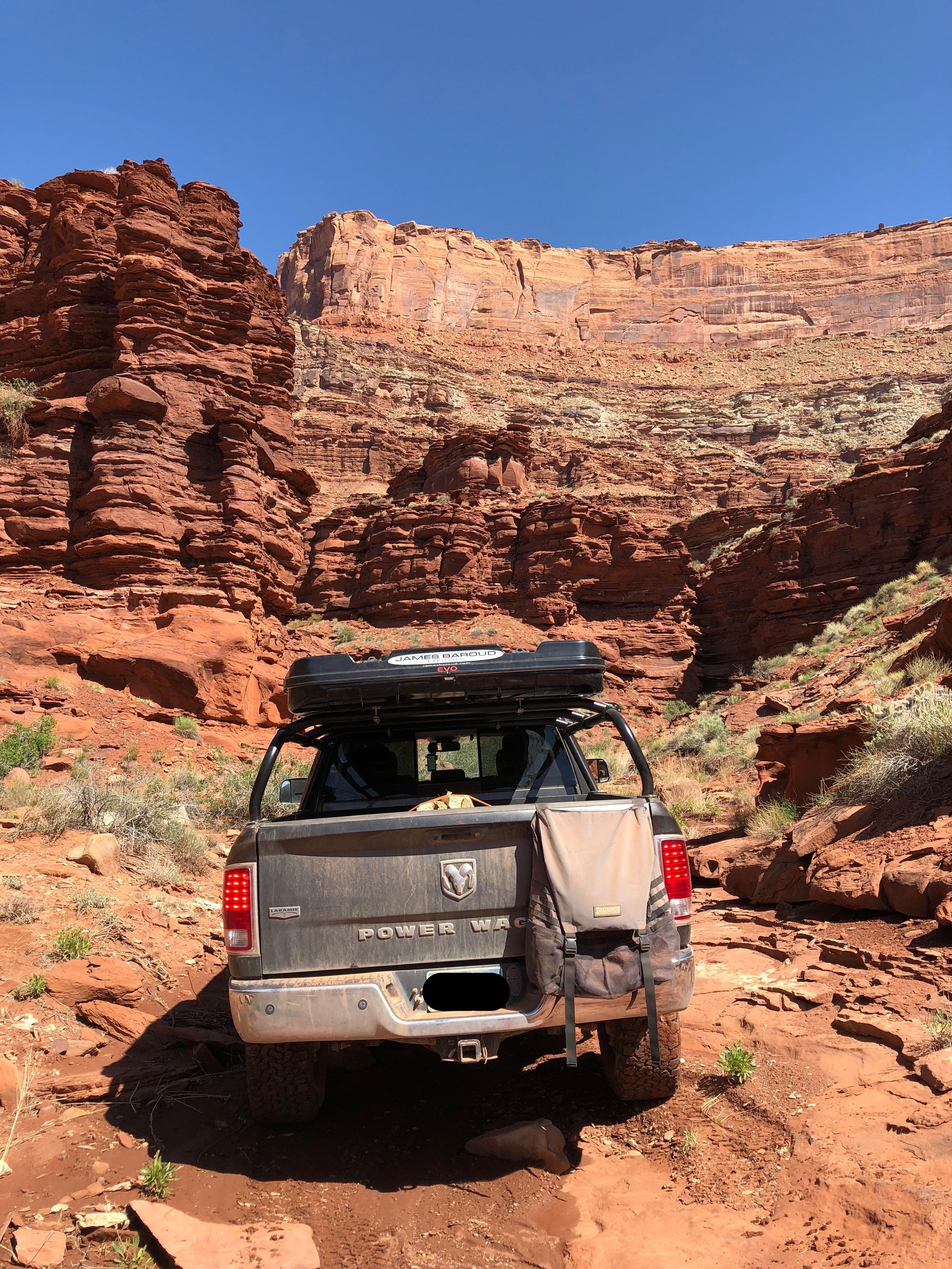 Rear view of the Power Wagon parked below a red sandstone wall, roof box overhead