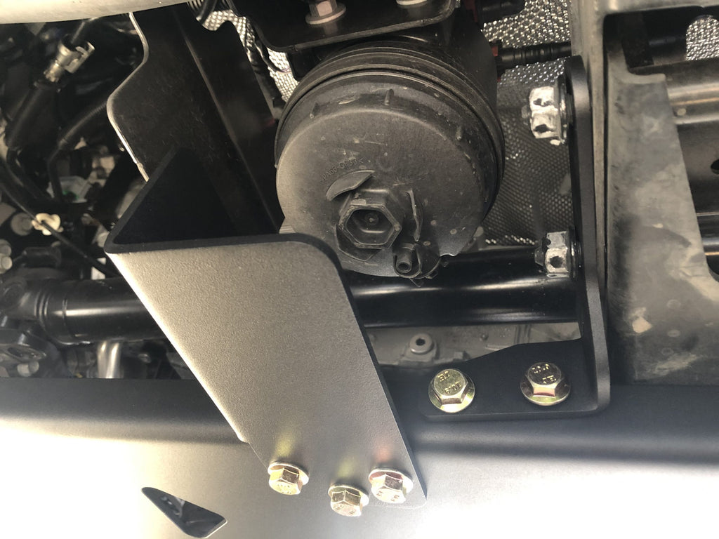 Plate corner offered up to the underbody during fitting, hardware in place