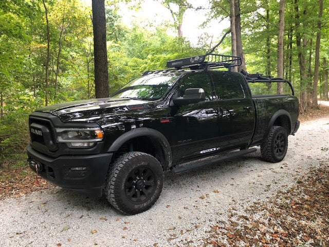 Black Power Wagon on a gravel drive in the woods, rack carrying a light bar and a basket