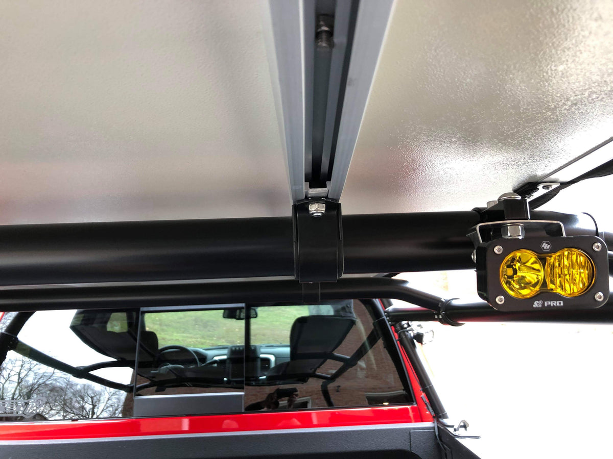 An amber-lens pod clamped to the rack bar, rack and cab visible behind
