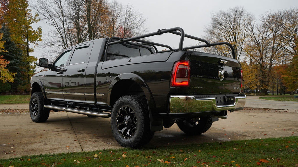 Black Ram crew cab on a driveway in fall, seen from the rear quarter with the rack over the bed