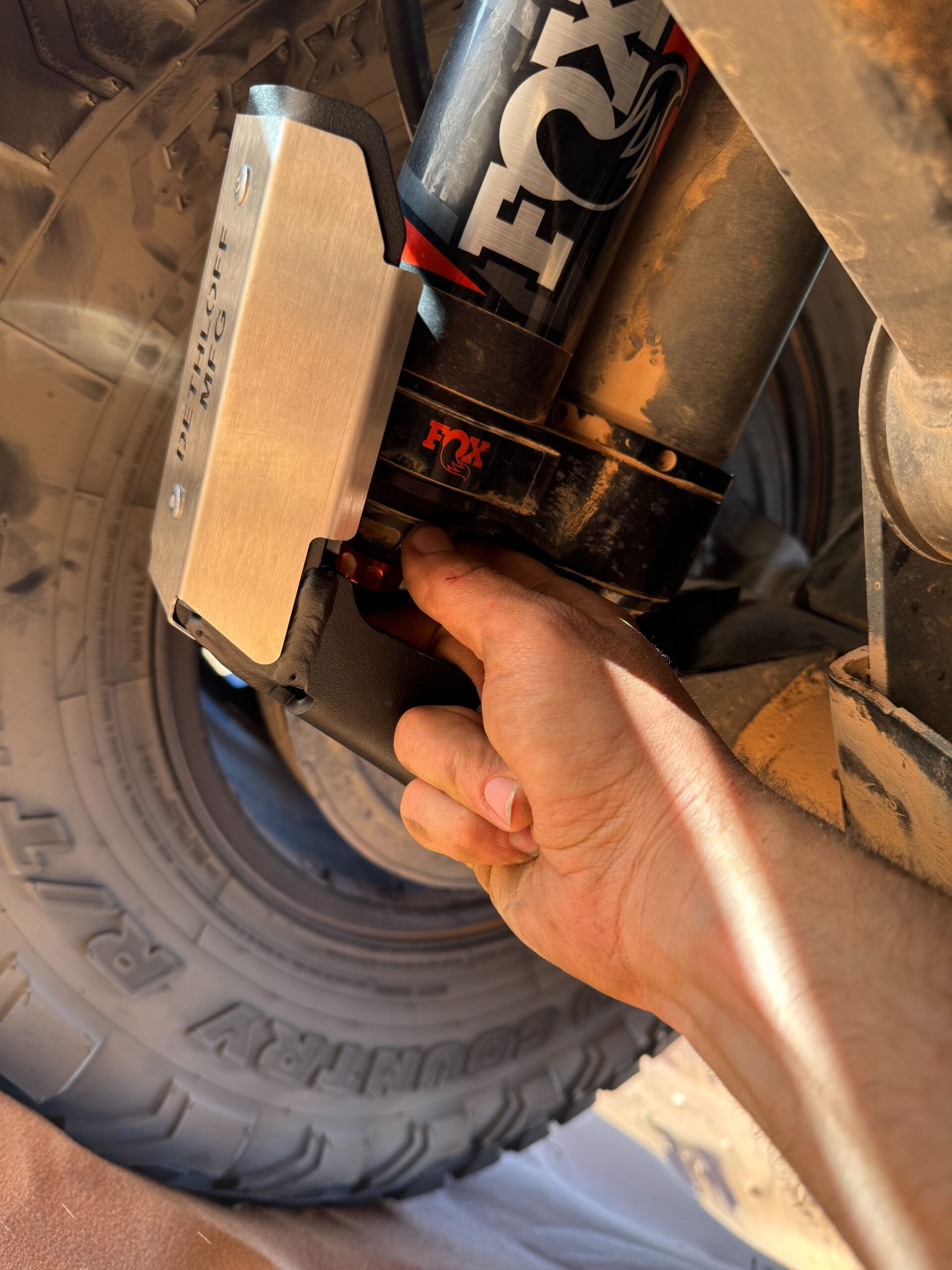 A hand fitting the guard around the shock above the tire