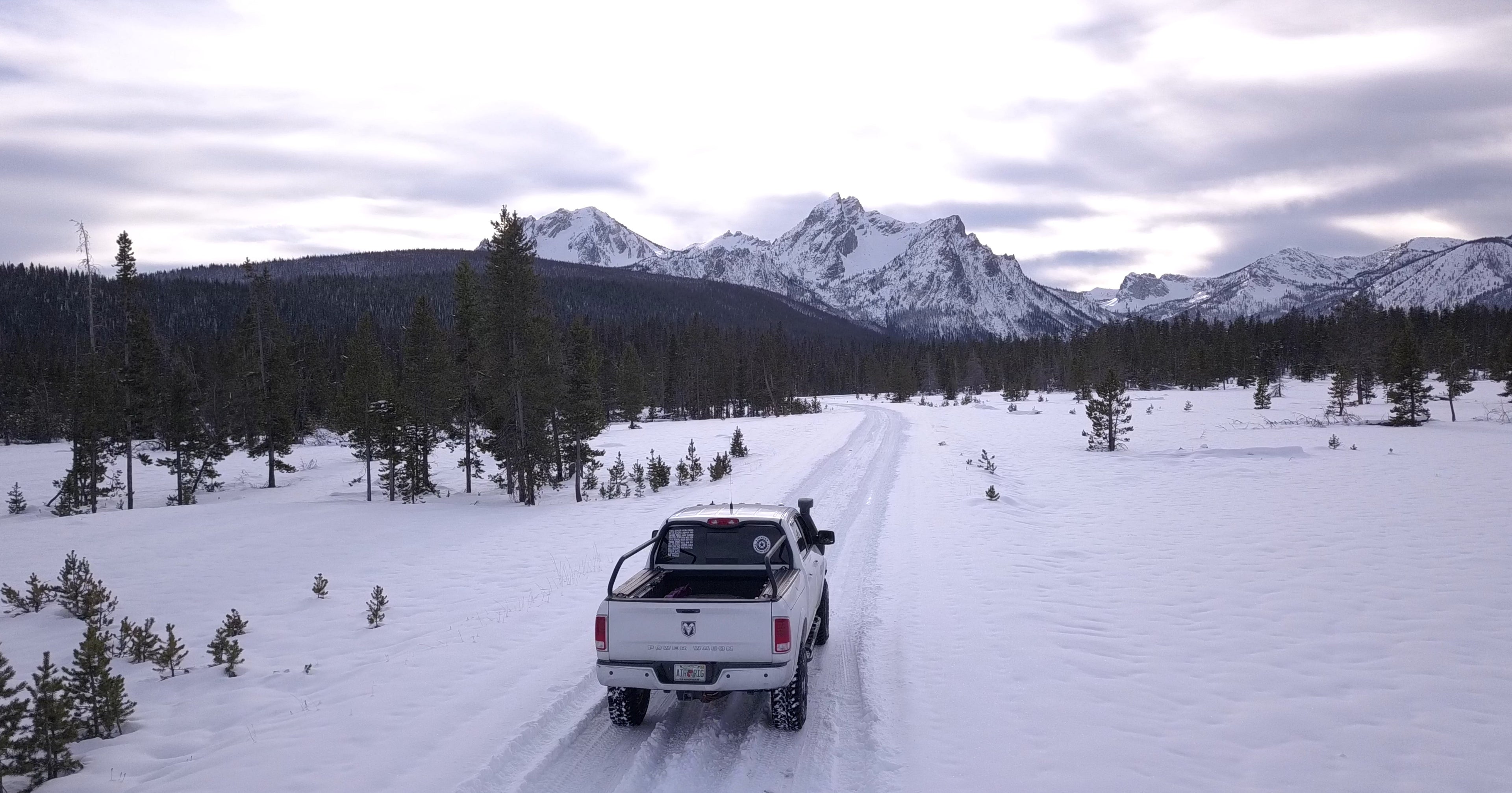 White Ram driving a snow-covered road toward jagged snowy peaks