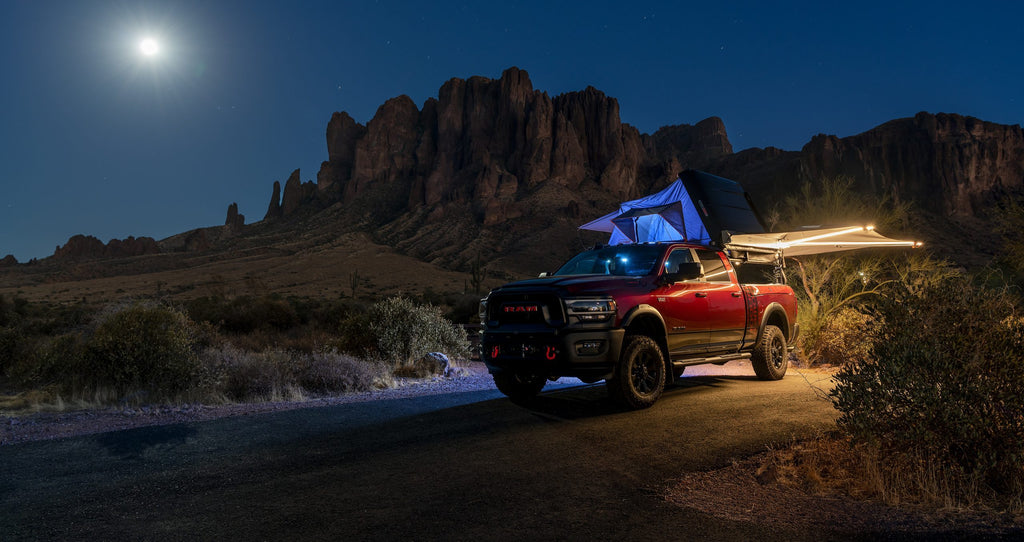 Red Ram on a desert road under a full moon, roof tent and awning open