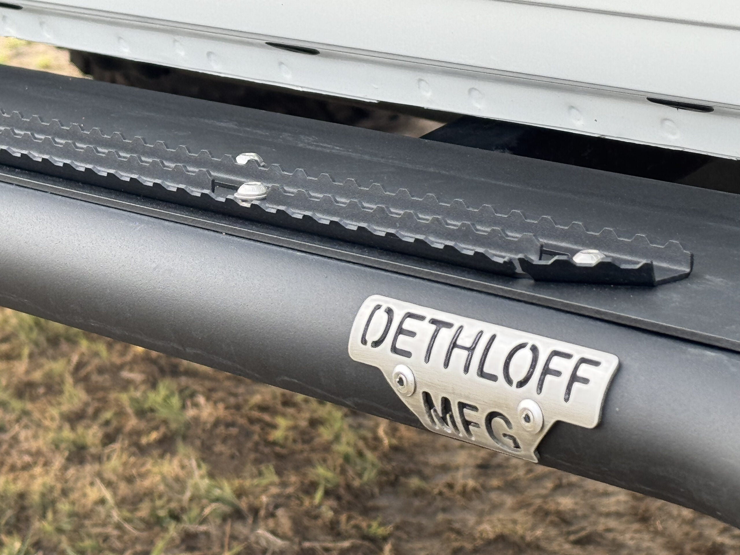 Close view along the slider's top plate, toothed grip strips and badge in view