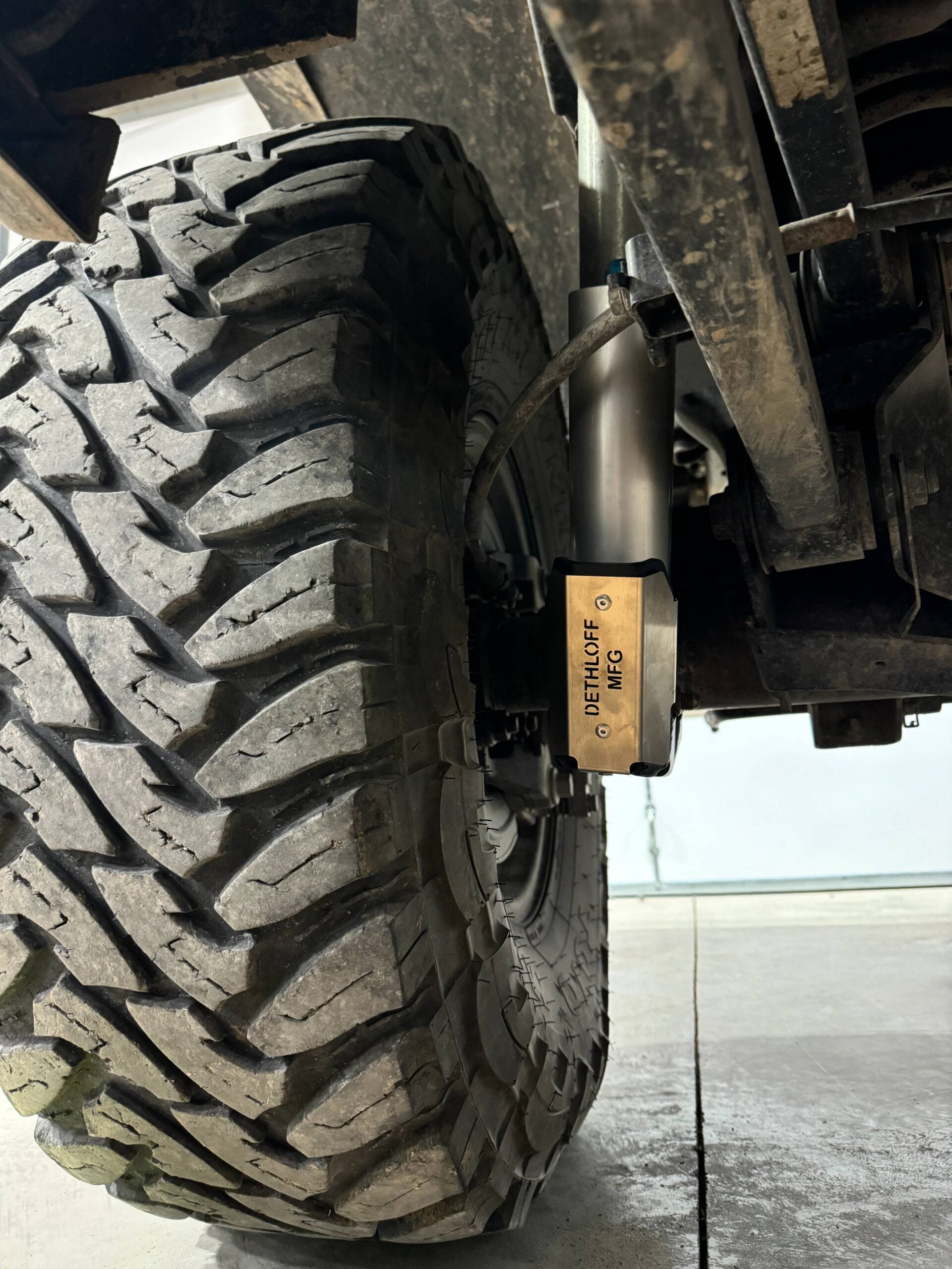 The fitted guard behind a muddy rear tire, seen from below