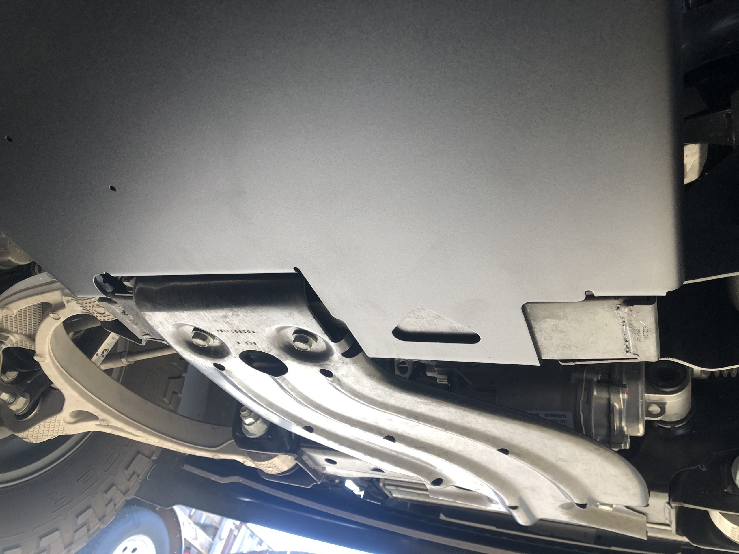 The plate fitted, seen from the side past the front suspension arm