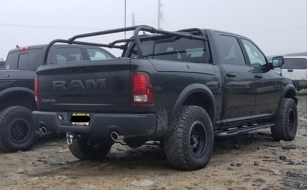 Rear quarter of the black Ram in a gravel lot, rack rails above the bedsides