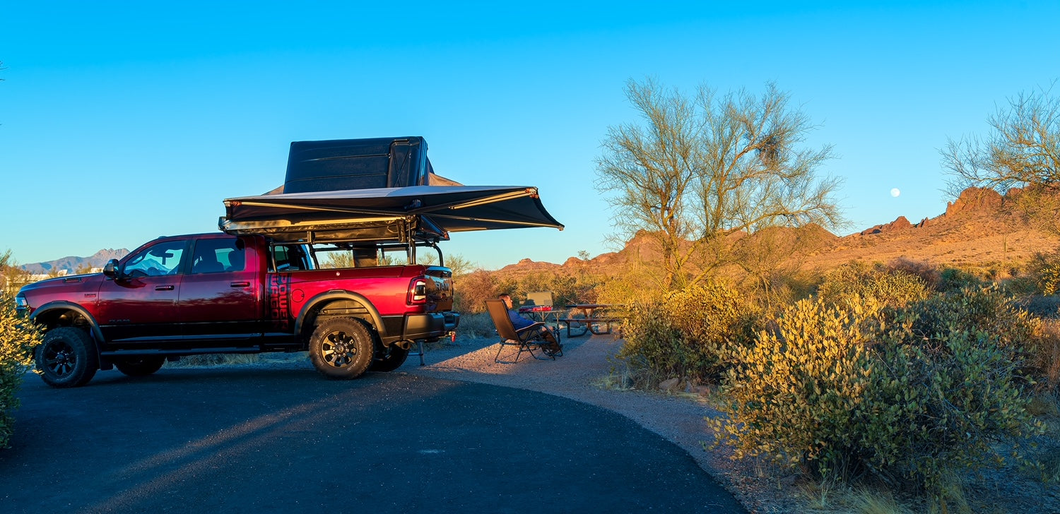 Red Ram at a desert campsite at dusk, roof tent and awning both open off the rack