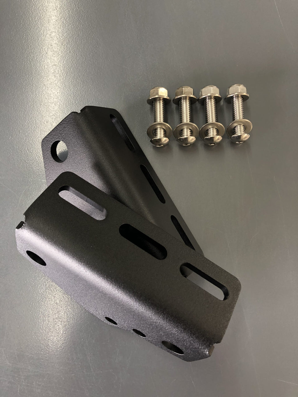 A folded bracket on a steel bench with four bolts beside it