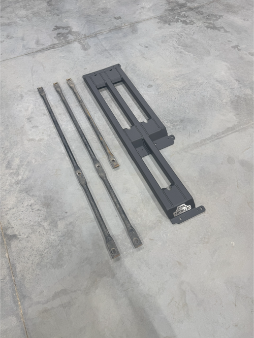 The three-bar frame and its support bars laid out on a concrete floor