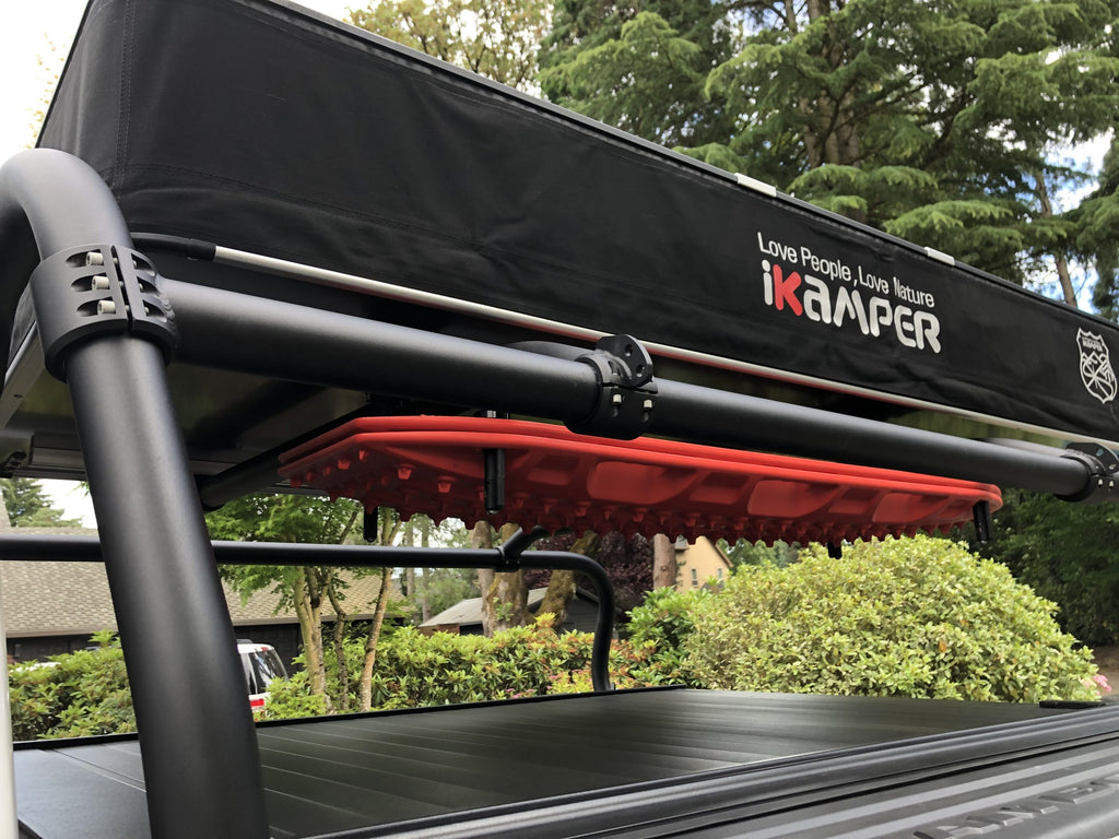 Close view of a rolled awning clamped to the rack's side rail above the bed