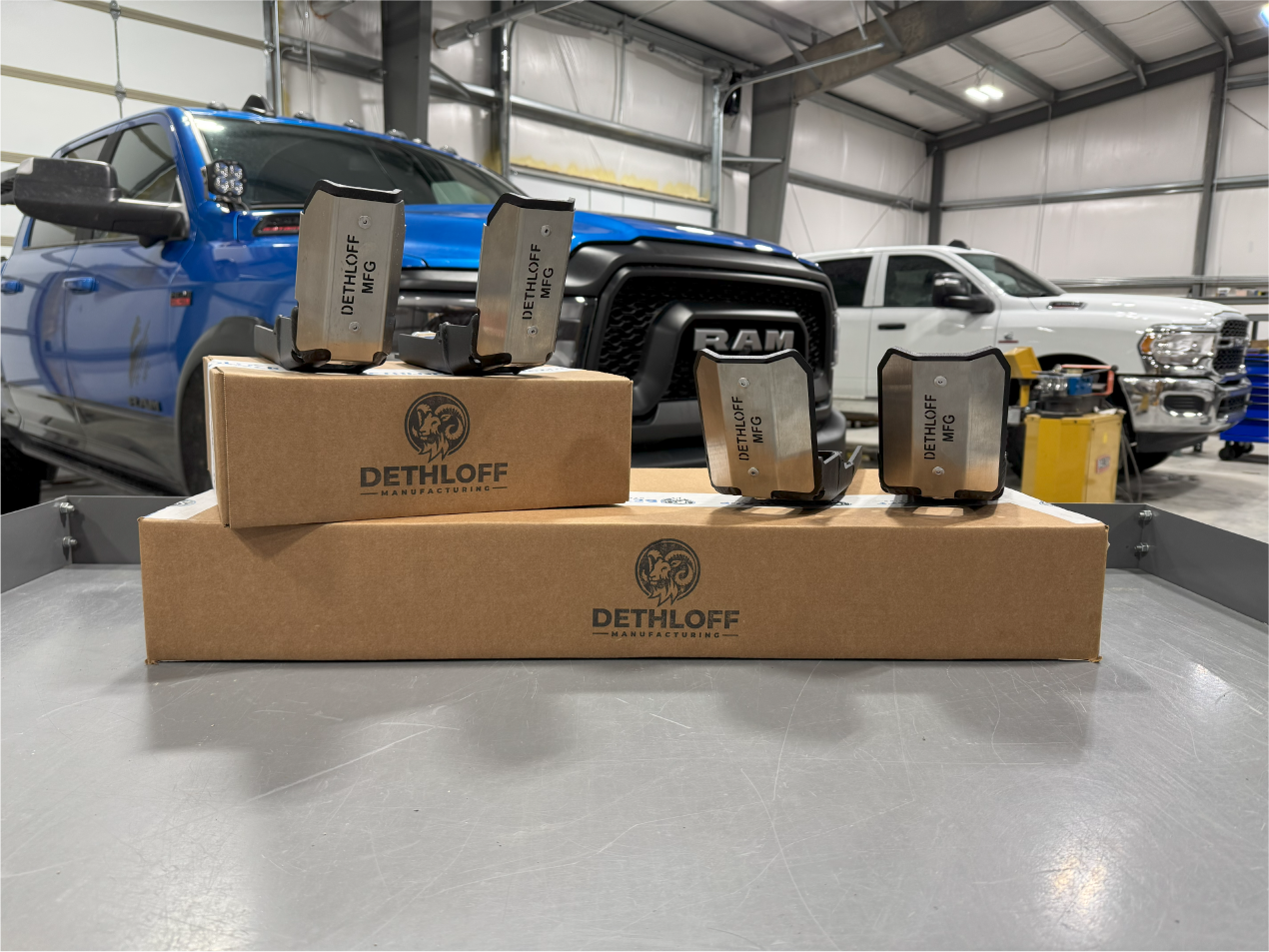 Four guards and a Dethloff box arranged on a bench, trucks in the shop behind