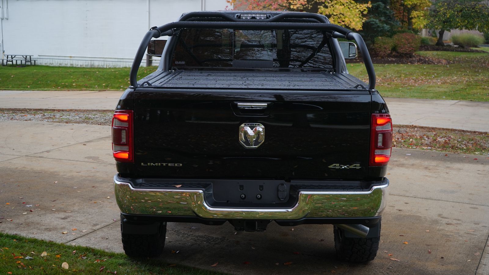Straight rear view of the black Ram on a driveway, rack legs rising above a closed tonneau